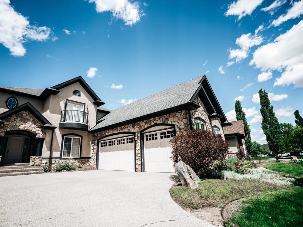 Finished asphalt shingle roof on a large stone and stucco Calgary home