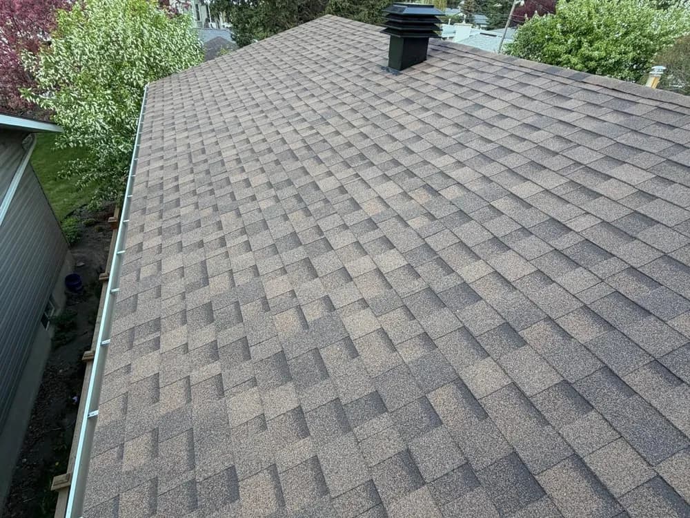 Completed asphalt roof with a new ridge cap and roof vent