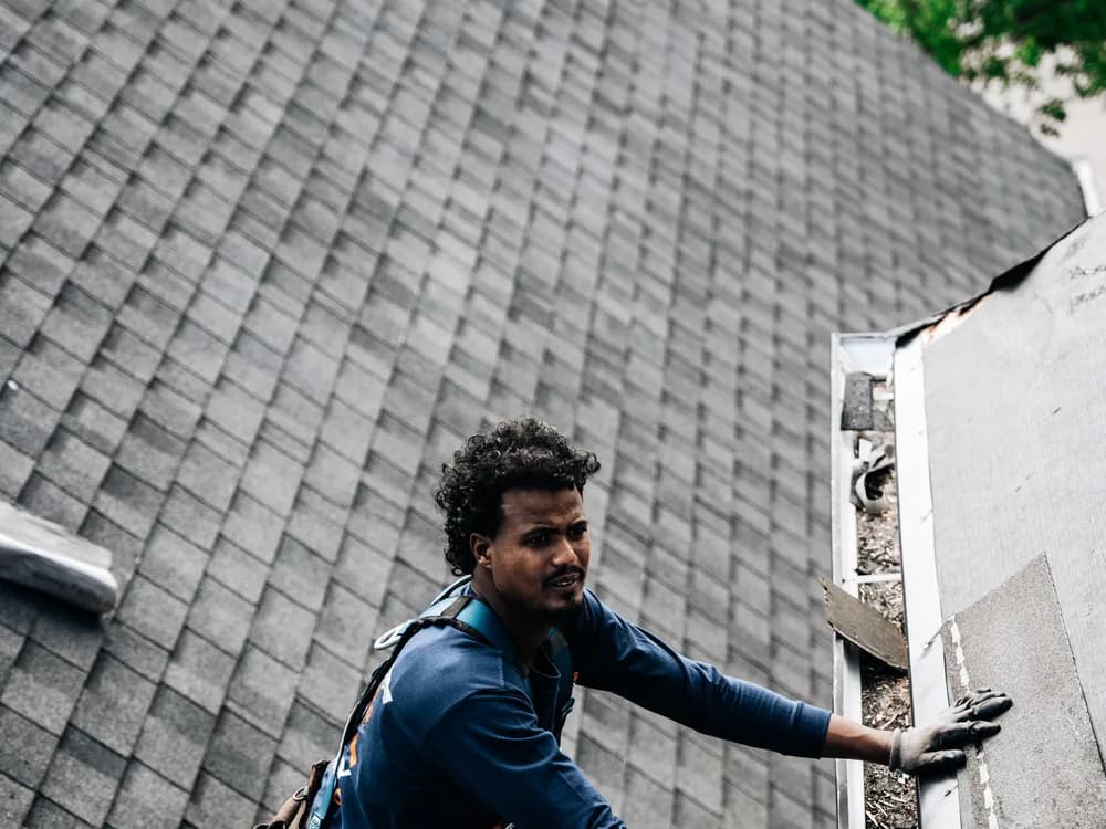 Roofer working on the flashing where a roof slope meets a wall