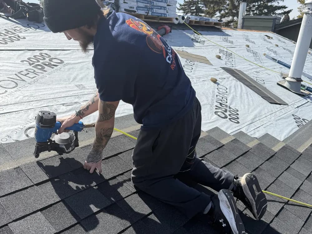 Calgary Roofing Pro crew member nailing new asphalt shingles into place