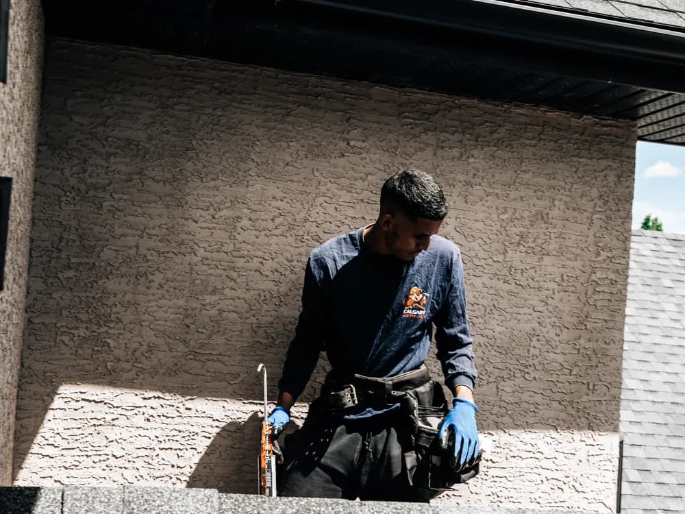 Roofer repairing the junction where a roof meets a stucco wall