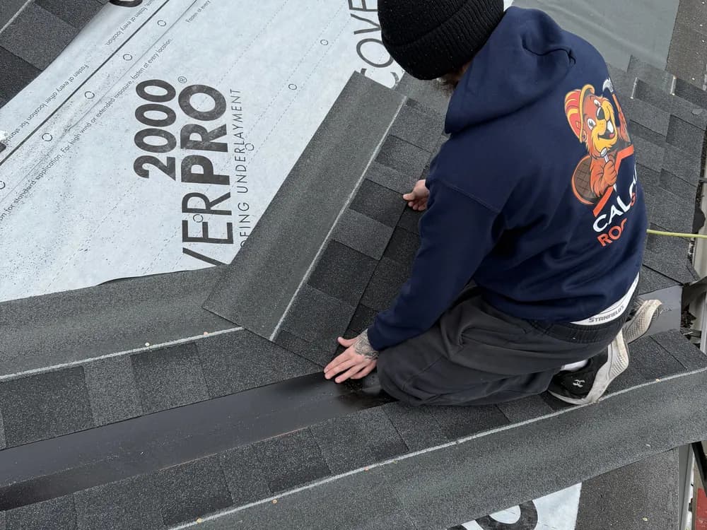 Crew member installing synthetic underlayment and starter shingles on a roof