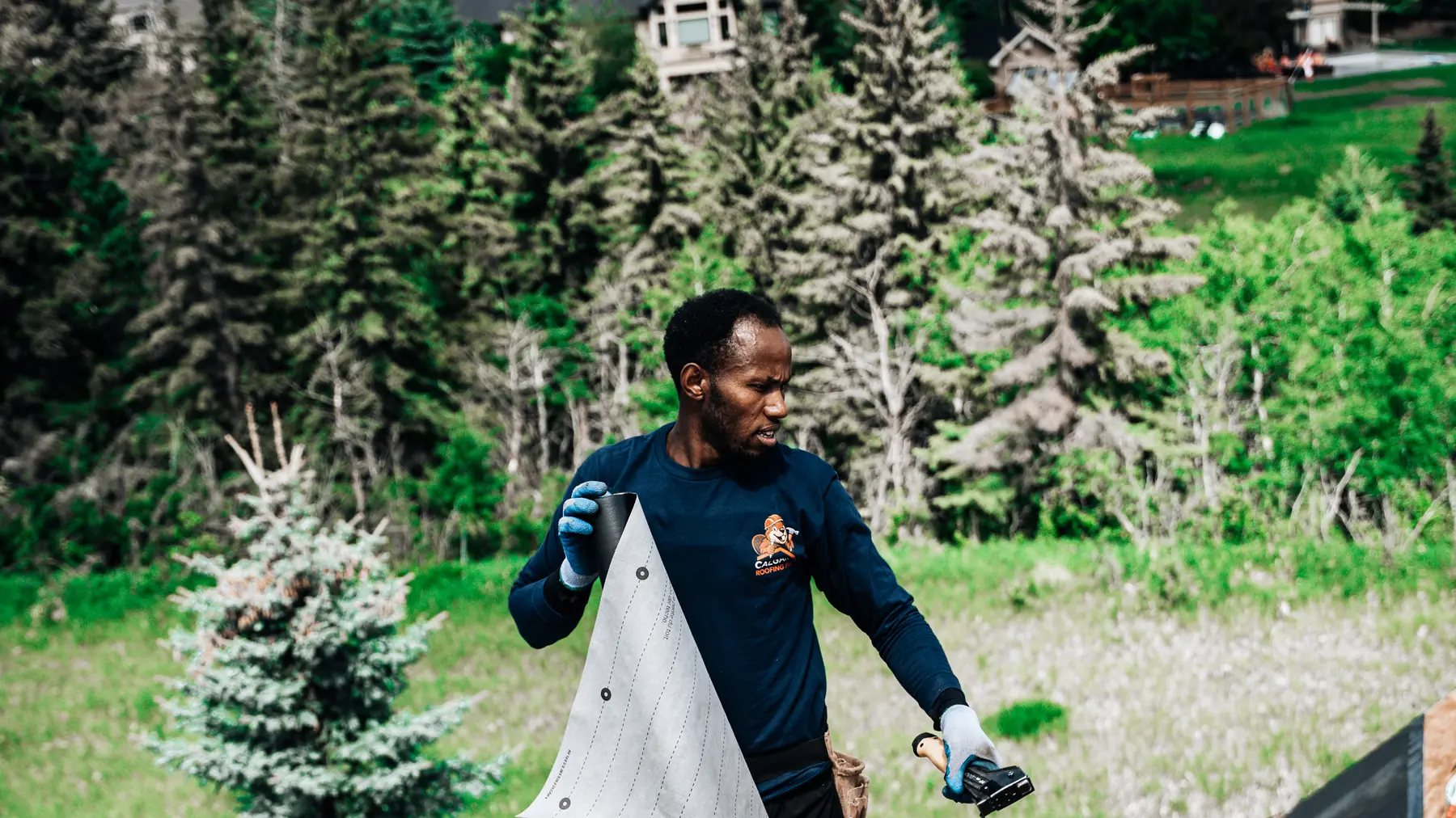 Calgary Roofing Pro crew member carrying underlayment across a roof