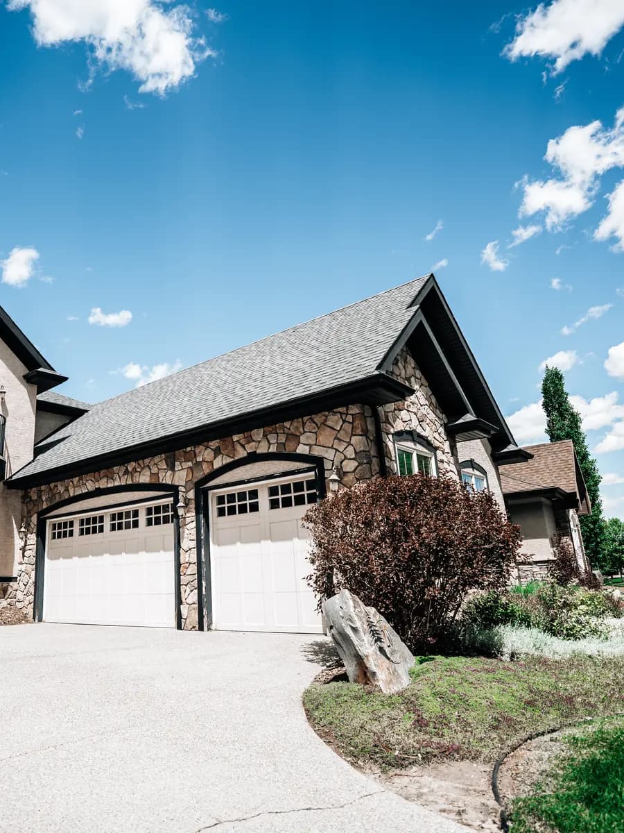 Finished asphalt shingle roof on a stone and stucco Calgary home, completed by Calgary Roofing Pro