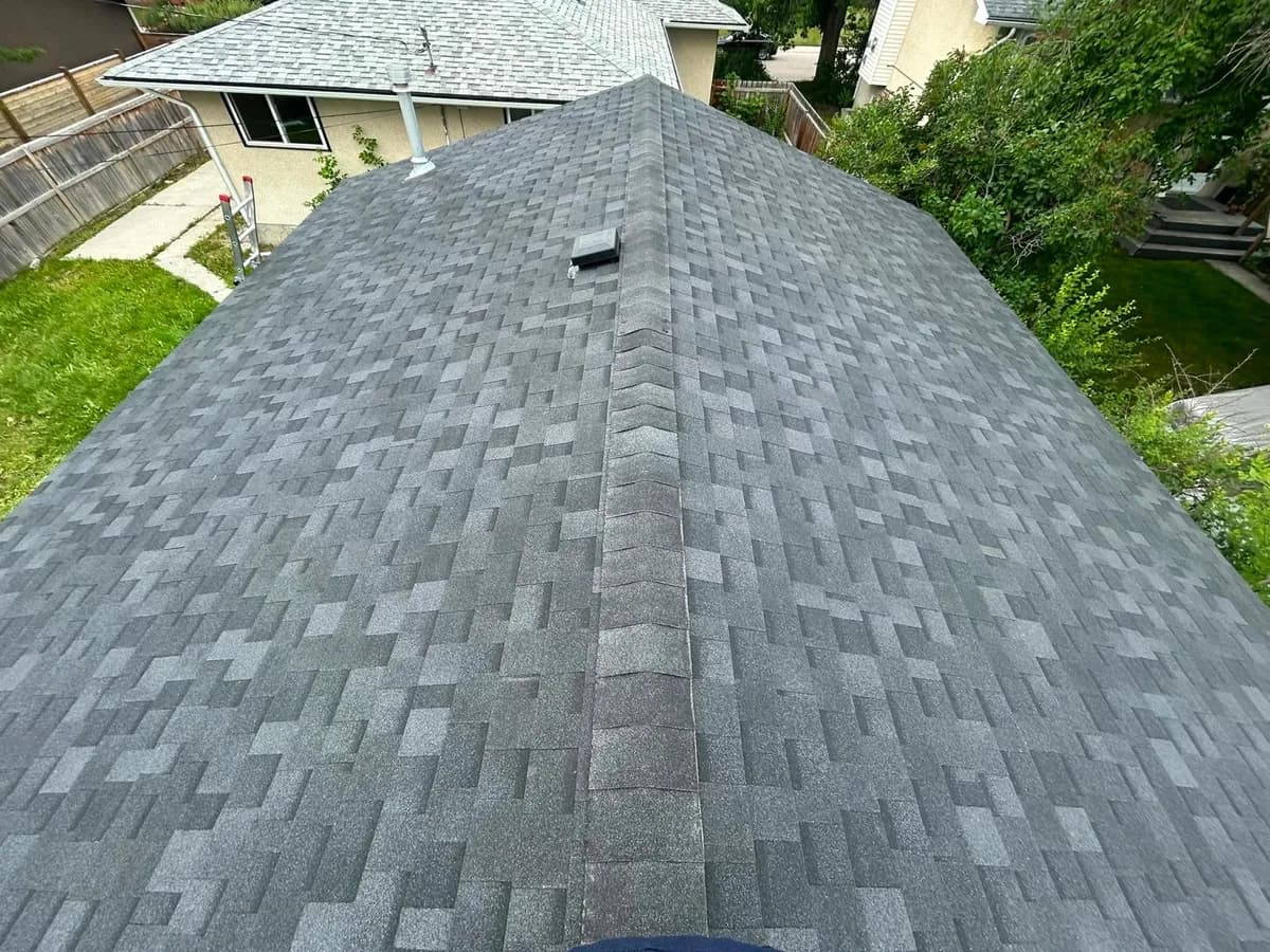 The same roof after replacement with new charcoal architectural shingles, a new hip cap and a new black roof vent