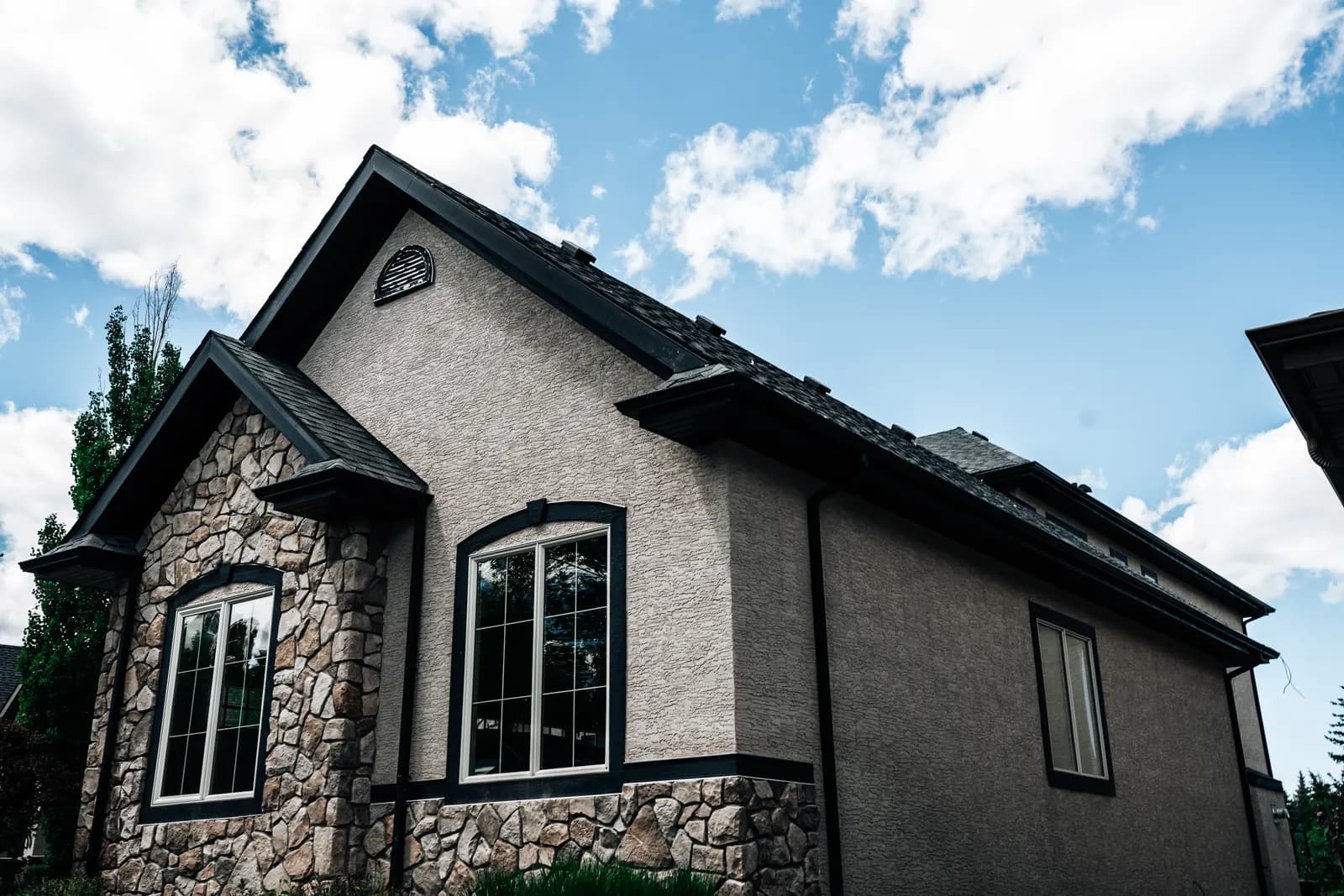 Side of a stone and stucco home with a new roof