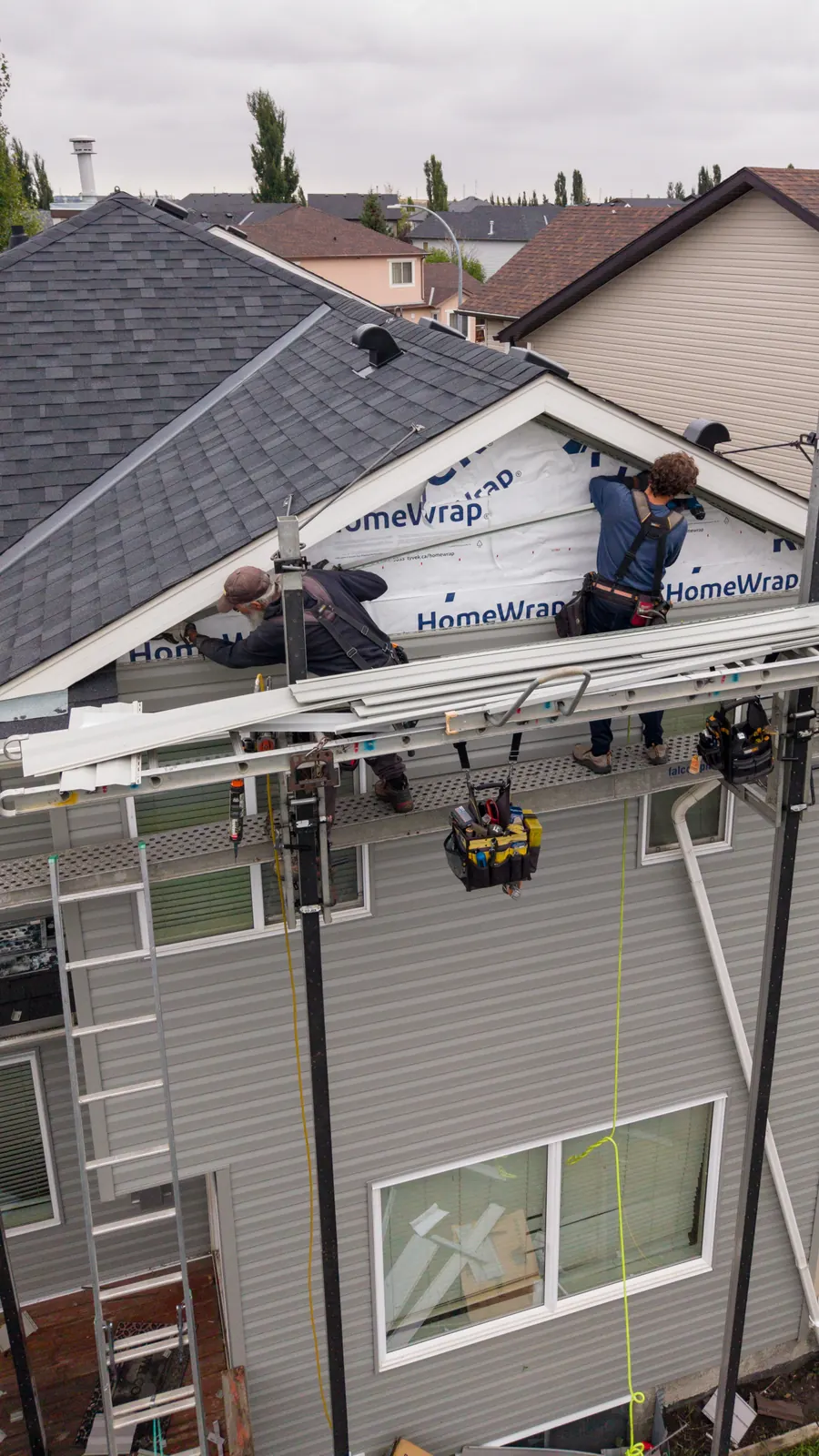 Crew on scaffolding installing house wrap