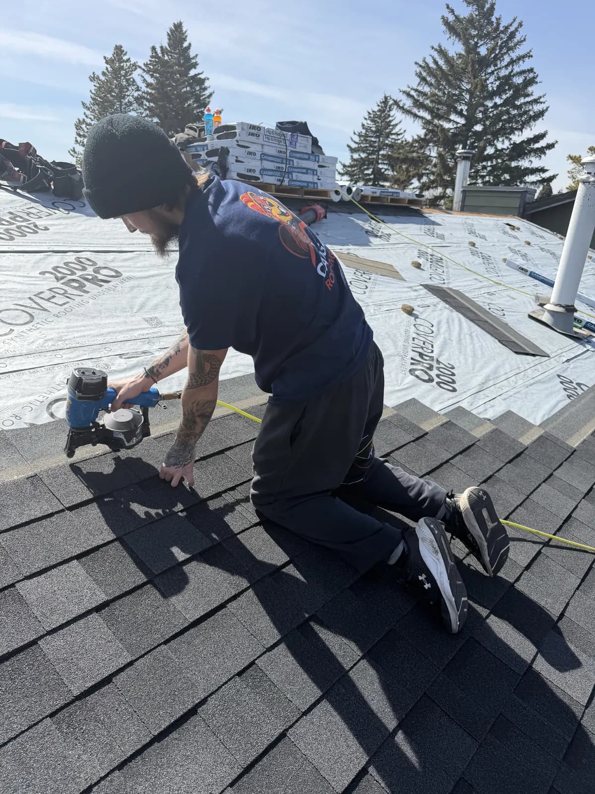 Roofer nailing new asphalt shingles with a nail gun